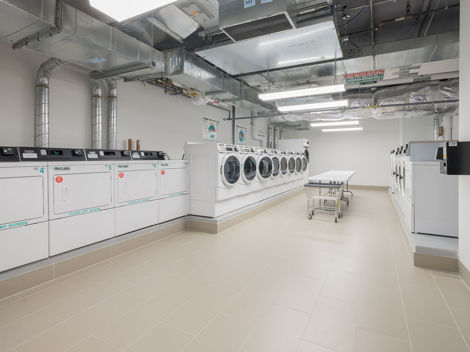 Clean on sight laundry room with washers, dryers, and folding tables at 685 First Avenue, Murray Hill apartments rentals. 